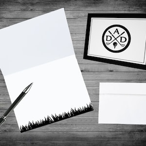 May include: A black and white card with a golf-themed design. The card features a circle with crossed golf clubs and the letters "A D D" inside. The card is on a wood background.