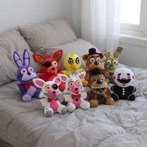 May include: A collection of nine plush toys featuring various characters including a purple rabbit, a red fox with an eye patch, a yellow bird, a brown bear with a top hat, a green rabbit, a white and pink fox, and a black and white puppet figure.