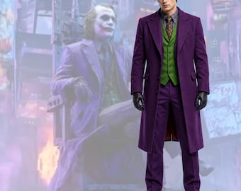 Può includere: Un abito viola composto da un cappotto lungo, pantaloni e un gilet verde con una cravatta marrone a fantasia. L'insieme include una camicia azzurra e guanti in pelle nera. L'outfit è indossato da una persona con capelli scuri.