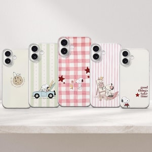 Puede incluir: Cinco fundas para teléfono con diseños de Snoopy y Woodstock. La primera es crema con una galleta, la segunda tiene rayas verdes y un coche, la tercera es de cuadros rosas con estrellas, la cuarta tiene rayas rosas y Snoopy pintando, y la quinta es blanca con el texto good things take time.