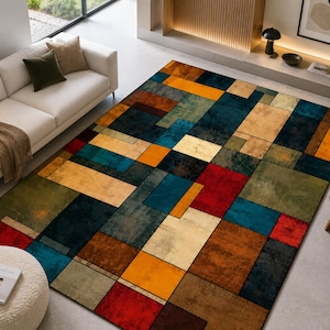 Peut inclure: Un tapis rectangulaire présentant un motif géométrique composé de blocs imbriqués dans des tons bleu profond, orange vif, rouge sourd, vert olive et crème. Le design se compose de formes rectangulaires variées avec une finition texturée.