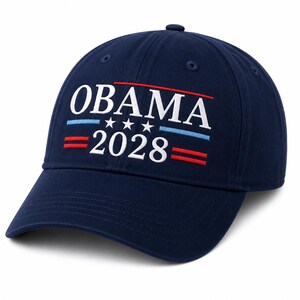 Pode incluir: Um boné de beisebol azul-marinho com texto bordado em branco que diz OBAMA 2028. O design inclui três pequenas estrelas brancas centralizadas entre as palavras e linhas horizontais vermelhas e azul-claras acima e abaixo.
