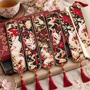 May include: Six rectangular bookmarks featuring intricate beadwork in black, red, and cream. Each bookmark displays a fox mask or fox figure, cherry blossoms, and traditional torii gates, finished with a red beaded tassel at the bottom.