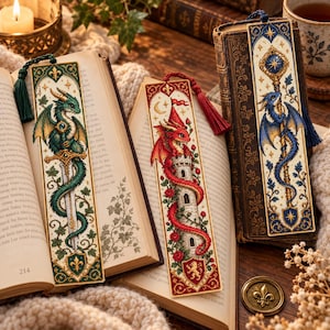 May include: Three rectangular fabric bookmarks featuring intricate cross-stitch embroidery. One depicts a green dragon coiled around a sword, one a red dragon on a stone tower with roses, and one a blue dragon holding a staff, each with a tassel.