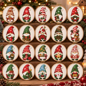 May include: A collection of twenty circular wooden embroidery hoops, each containing a cross-stitch design of a gnome in various holiday-themed outfits and poses, including holding gingerbread, lanterns, gifts, stars, and bells on white fabric.