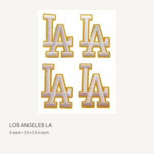 May include: A 4-pack of embroidered patches featuring the letters LA in white with a yellow border. Each patch measures 3.5 inches by 2.5 inches. The design consists of the overlapping letters L and A in a block font style with a thick yellow outline.