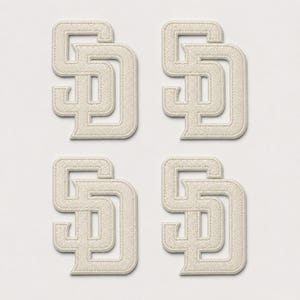 May include: Four identical off-white embroidered patches, each featuring the interlocking letters SD in a block font style. The patches have a raised, textured surface with a stitched border, arranged in a two-by-two grid pattern on a plain background.