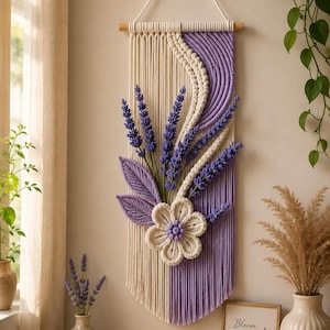 May include: A macrame wall hanging featuring cream and lavender cotton cords, a central six-petaled flower, and three-dimensional lavender sprigs. The design includes a curved section of wrapped cord and a wooden dowel for hanging.