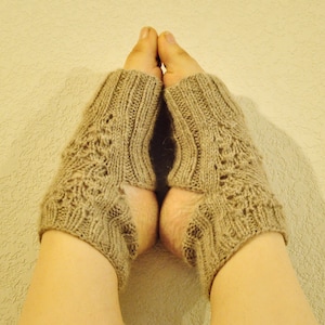 May include: A pair of beige knitted ankle warmers with a lacy pattern.