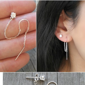 Peut inclure: Boucles d'oreilles en chaîne argentée avec un petit clou en pierre précieuse transparente et une barre pendante. Les boucles d'oreilles sont présentées sous plusieurs angles, dont un gros plan et sur une oreille. Design minimaliste et élégant.