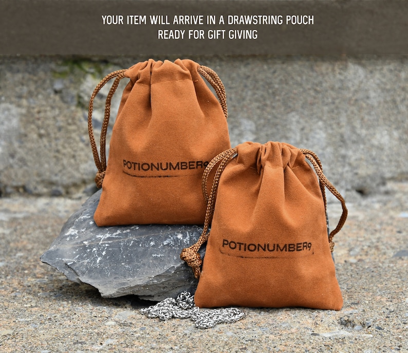 Pu&ograve; includere: Due sacchetti marroni con coulisse con la scritta "POTIONNUMBER9" stampata. I sacchetti sono realizzati in un materiale morbido e hanno coulisse marroni. Una catena d'argento &egrave; visibile davanti ai sacchetti. Il testo "YOUR ITEM WILL ARRIVE IN A DRAWSTRING POUCH READY FOR GIFT GIVING" &egrave; in alto.