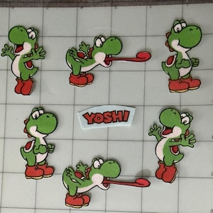 May include: A collection of six embroidered patches featuring the green character Yoshi in various poses, including two with extended tongues, and one rectangular patch with the red text YOSHI on a light blue background, arranged on a grid.