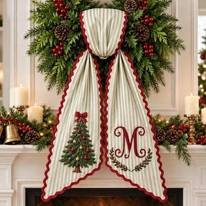 Peut inclure: Une guirlande décorative en tissu à rayures crème et vert sauge avec un bord festonné rouge. Le panneau gauche présente un sapin de Noël vert avec des boules rouges et dorées, tandis que le panneau droit porte une lettre M brodée en rouge.