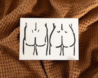 May include: A rectangular white card featuring a black ink line drawing of two sets of human buttocks side by side. The illustration uses simple, bold strokes to outline the shapes, creating a minimalist graphic representation on a plain white background.
