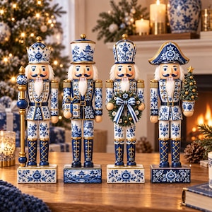 Puede incluir: Cuatro figuras de cascanueces con un patrón floral azul y blanco que recuerda a la porcelana. Cada figura viste un uniforme con detalles dorados, una barba blanca y se apoya sobre una base rectangular con motivos florales azules y blancos.