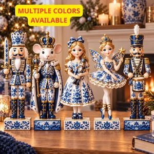 Può includere: Un set di cinque statuette decorative raffiguranti un soldato schiaccianoci, un re topo, una ragazza che tiene un piccolo schiaccianoci, una fata con le ali e un soldato tamburino. Ogni figura presenta un motivo floreale blu e bianco con dettagli oro.