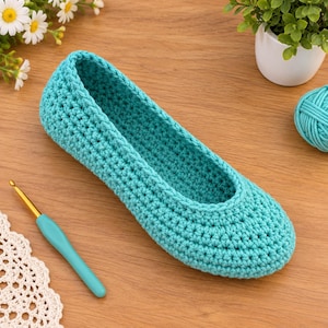 Puede incluir: Una zapatilla de ganchillo de color turquesa hecha con un patrón de punto denso y uniforme. La zapatilla presenta una puntera redondeada y una abertura baja. Junto a la zapatilla hay un ganchillo turquesa a juego con punta de metal dorado.