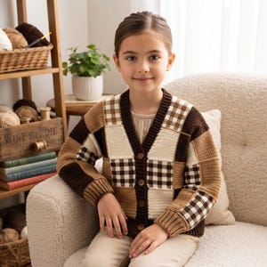 May include: A long-sleeve V-neck cardigan featuring a patchwork design of solid dark brown, tan, and cream-colored squares alongside brown and white gingham checkered squares. The garment includes a dark brown ribbed trim and four brown buttons.