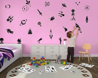 May include: A set of black vinyl wall decals featuring various space-themed illustrations including rockets, planets, stars, an astronaut, a telescope, and alien figures. These individual adhesive graphics are designed for application on flat surfaces.