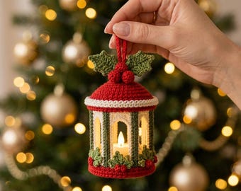 May include: A crocheted Christmas lantern ornament featuring a red roof and base, cream-colored arches, and dark green pillars. The top is decorated with two green crocheted holly leaves and three red berries, with a small LED candle inside.