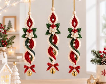 May include: Three hanging macrame ornaments featuring twisted red, green, and cream cord patterns. Each piece is accented with a white flower, green leaves, red berries, small white pearls, a red ribbon bow, and a gold jingle bell at the base.