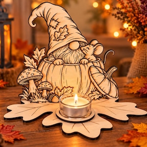 May include: A laser-cut wooden decorative piece featuring a gnome wearing a patched hat and a small mouse sitting inside a pumpkin. The design includes mushrooms, leaves, and an acorn, with a circular glass holder for a tea light candle.