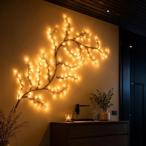 Puede incluir: Una lámpara de pared decorativa con forma de rama, que presenta una estructura oscura y delgada adornada con numerosas luces LED de tonos cálidos que emiten un suave resplandor dorado, creando una silueta intrincada y extendida en la pared.