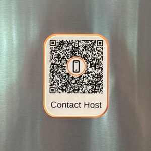 May include: A rectangular white magnet with rounded corners and an orange border. It features a black and white QR code in the center with a small smartphone icon inside, and the text Contact Host printed in black below the code.
