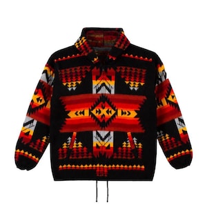 May include: A black zip-up fleece jacket featuring a vibrant geometric pattern in shades of red, orange, yellow, and white. The design includes repeating triangular and diamond motifs across the chest, sleeves, and collar, with a drawstring hem.