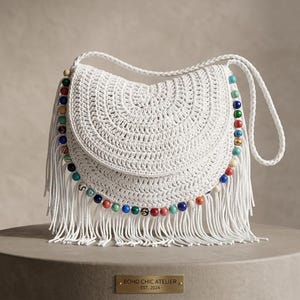 May include: A white crocheted shoulder bag featuring a curved flap, a braided strap, and long fringe trim along the bottom edge. The bag is decorated with a row of multicoloured beads in shades of blue, red, green, and gold along the front seam.