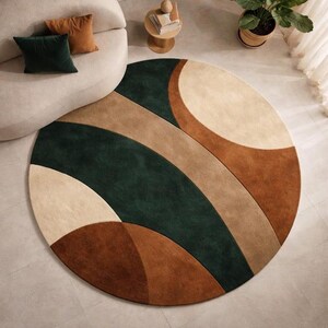 May include: A large circular area rug featuring a bold geometric pattern with sweeping curved sections in deep forest green, warm terracotta, tan, and cream colors. The rug has a soft, plush texture and covers a significant portion of the floor space.
