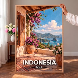 Puede incluir: Una lámina de arte enmarcada que muestra una vista panorámica de la costa de Indonesia desde un balcón, con buganvillas rosas, macetas de terracota y una alfombra estampada. El texto INDONESIA ASIA aparece impreso en blanco en la parte inferior.