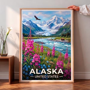 以下が含まれることがあります： アメリカ合衆国アラスカの風景を描いた額装済みの縦型ウォールアートプリント。雪を頂いた山々、ヒグマ、ハクトウワシ、そして手前に鮮やかなピンク色のヤナギランが咲く、谷を流れる川の風景が描かれています。