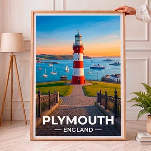 May include: A framed travel poster featuring a red and white striped lighthouse overlooking a harbor in Plymouth, England. The scene includes sailboats, a ferry, and distant naval ships under a sunset sky, with the text PLYMOUTH ENGLAND at the bottom.
