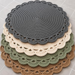 May include: A stack of four circular crochet doilies featuring a solid center and a scalloped edge. The colors from top to bottom are dark gray, cream, sage green, and light brown. Each piece is crafted with a consistent circular stitch pattern.