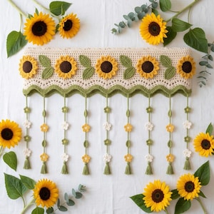 Pode incluir: Uma sanefa de croché cor de creme com uma fila de seis girassóis grandes com centros castanho-escuros e pétalas amarelas, intercalados com folhas verdes. Sob a borda recortada pendem nove fios verticais decorados com pequenas flores.