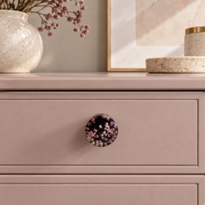 Blommiga skåpknoppar med rosa ljungblommor i svart harts