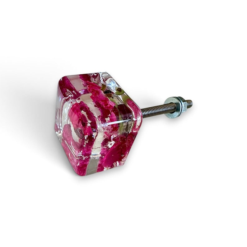 May include: A square cabinet knob made of clear resin with embedded deep pink rose petals. The knob features a smooth, polished finish and is attached to a threaded metal bolt with a small circular washer and a nut at the base of the hardware.