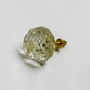 May include: A faceted, clear resin cabinet knob with a spherical shape, containing embedded dried white dandelion seeds. The knob features a gold-toned metal base and a threaded screw attachment extending from the back for mounting purposes.