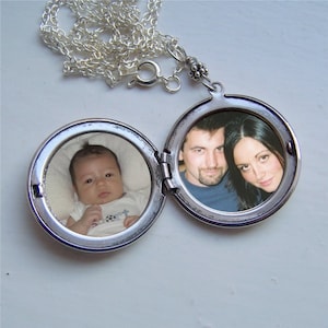 May include: Open silver locket necklace with two circular compartments, each holding a photograph. One side features a baby, the other a couple. The locket is on a silver chain.