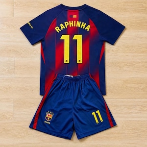 Puede incluir: Un conjunto de fútbol azul y rojo que incluye camiseta y pantalón corto. La camiseta muestra el nombre RAPHINHA y el número 11 en amarillo en la espalda. El pantalón azul tiene rayas laterales rojas, el número 11 en amarillo y un escudo con BRASIL.
