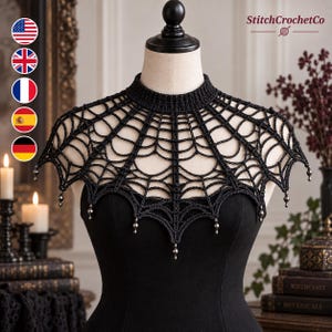 Könnte beinhalten: Ein schwarzer Häkelkragen mit Spinnennetz-Muster, hohem Kragen und kleinen Metallperlen, die am unteren Rand hängen. Das Stück wird auf einer Schaufensterpuppe präsentiert, die ein schlichtes schwarzes Kleidungsstück trägt.