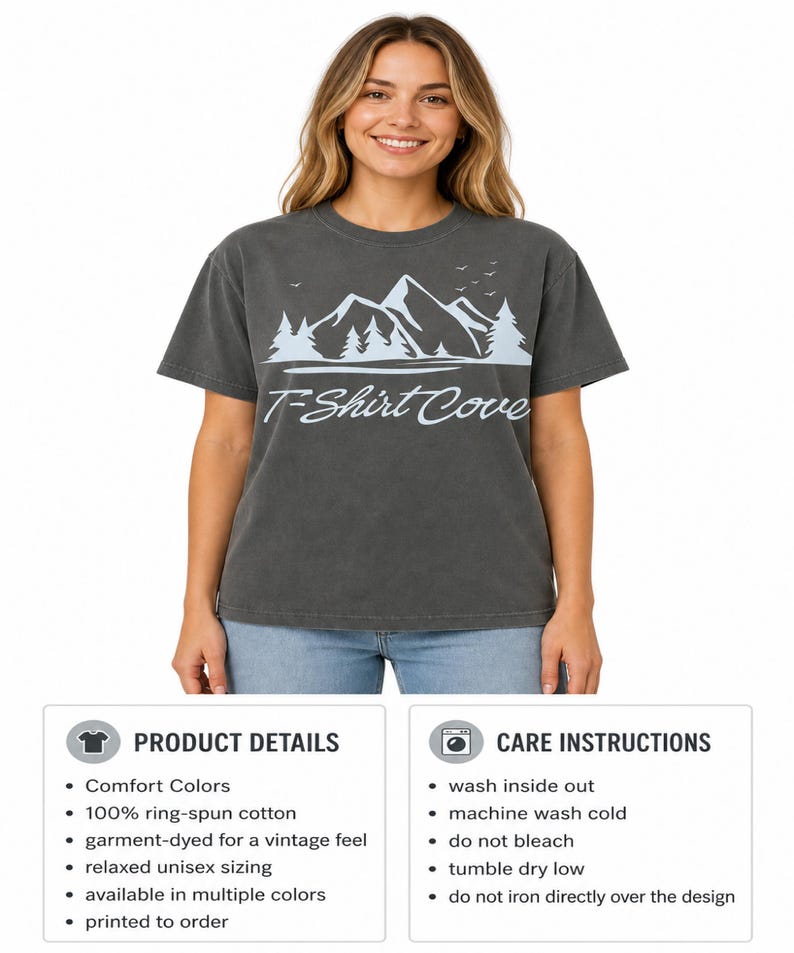 Op de afbeelding: Een antracietgrijs T-shirt met korte mouwen en een lichtblauwe afbeelding van bergtoppen, dennenbomen en vogels boven de tekst T-Shirt Cove in een cursief lettertype. Het shirt heeft een ronde hals en een relaxte pasvorm.