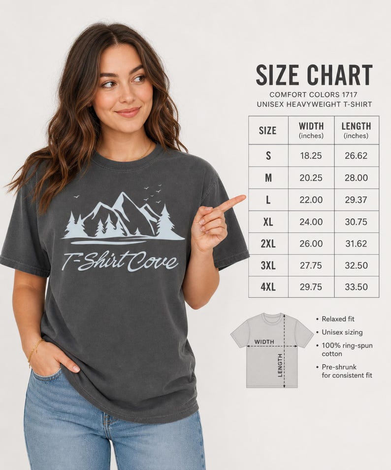 Op de afbeelding: Een antracietgrijs t-shirt met korte mouwen en een lichtblauwe afbeelding van bergen, dennenbomen en vogels boven de tekst T-Shirt Cove. Een maattabel toont de breedte- en lengtematen in inches voor de maten S tot en met 4XL.