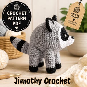 May include: A gray and white crocheted raccoon toy with black eye patches, ears, and feet. A black circular tag reads CROCHET PATTERN PDF, and a tan tag reads EASY TO FOLLOW Step-by-Step Instructions. The text Jimothy Crochet is at the bottom.