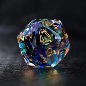 May include: A twenty-sided polyhedral die featuring a multi-colored, iridescent, glass-like finish. The die displays gold-colored engraved numbers and a small ghost icon on one of its triangular faces, reflecting light with vibrant blue, orange, and yellow hues.