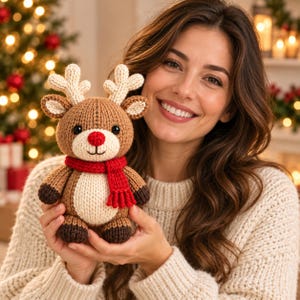 May include: A brown and cream-colored knit reindeer plush toy featuring a bright red nose, a matching red scarf, and dark brown hooves. The stuffed animal has textured antlers and a round belly, crafted with visible yarn stitches.
