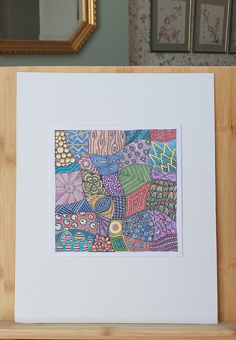 May include: A square drawing featuring a complex arrangement of colourful, hand-drawn geometric and organic patterns. The artwork includes various shapes like circles, zigzags, and floral motifs filled with vibrant shades of blue, pink, green, and yellow.