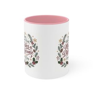 May include: A white ceramic mug with a soft pink interior. The exterior features a festive wreath design composed of pine branches, holly berries, pinecones, and gold stars. The text reads: Your Hard Work Makes a Difference Every Day.