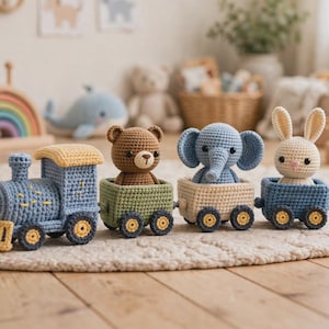 Könnte beinhalten: Ein gehäkeltes Spielzeugeisenbahn-Set bestehend aus einer blauen Lokomotive mit gelben Akzenten und drei kleinen Waggons. Jeder Waggon enthält ein anderes Stofftier: einen braunen Bären, einen blauen Elefanten und einen cremefarbenen Hasen mit langen Ohren.